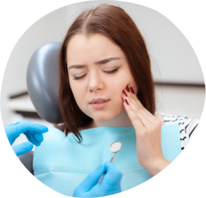 Woman in dental chair experiencing tooth pain, holding her cheek, while dentist prepares for examination with dental mirror.