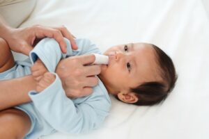 mother using fingers and cloth to clean baby's gums