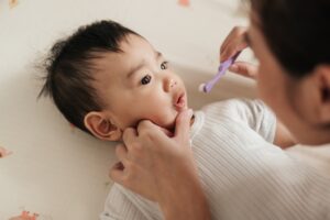 mother preparing to brush baby's teeth with infant toothbrush
