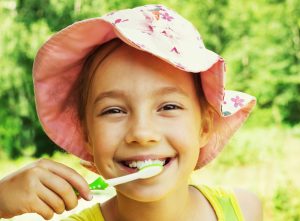 child brushing teeth outside in summer